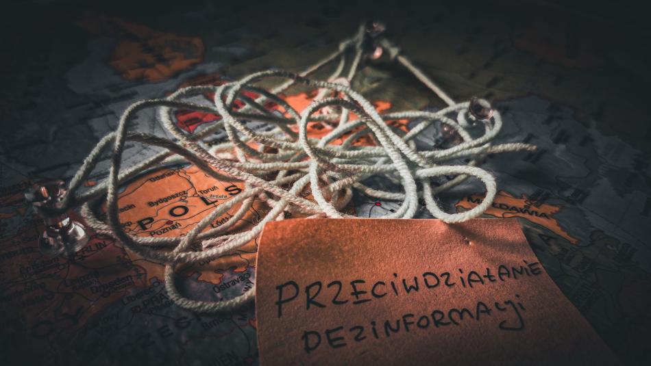 Splątane liny na mapie Polski i kartka z napisem Przeciwdziałanie dezinformacji.